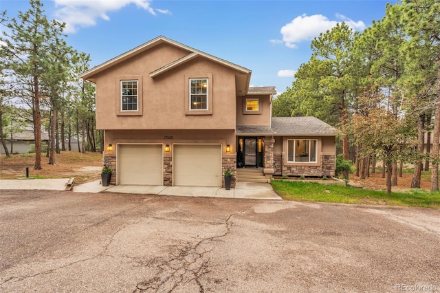 17540 Caribou Dr, Monument, CO 80132 - view of front of house with stone siding, stucco siding, driveway, and an attached garage