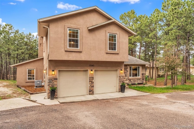 17540 Caribou Dr, Monument, CO 80132 - view of front facade with stone siding, stucco siding, central AC unit, and an attached garage