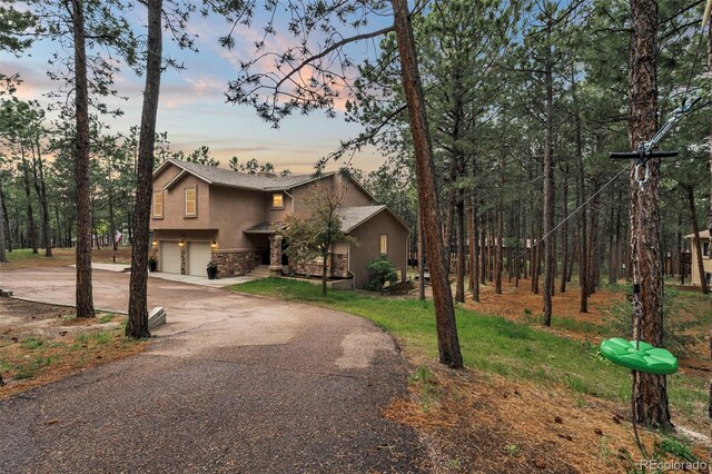 17540 Caribou Dr, Monument, CO 80132 - view of front of house with stucco siding, driveway, a garage, and stone siding