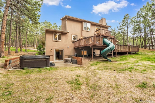 17540 Caribou Dr, Monument, CO 80132 - back of house featuring a hot tub, a chimney, a wooden deck, and stucco siding