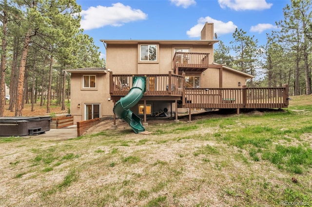 17540 Caribou Dr, Monument, CO 80132 - rear view of house with a hot tub, a chimney, a playground, stucco siding, and a wooden deck