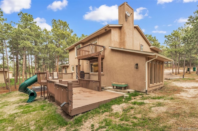 17540 Caribou Dr, Monument, CO 80132 - back of property featuring a balcony, a playground, stucco siding, a chimney, and a deck