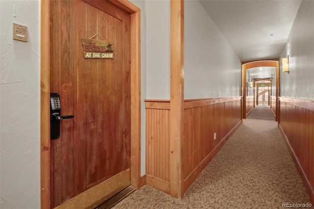 hall featuring carpet floors and wooden walls