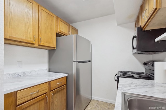 kitchen with light stone countertops, stainless steel fridge, electric range oven, sink, and light tile patterned floors