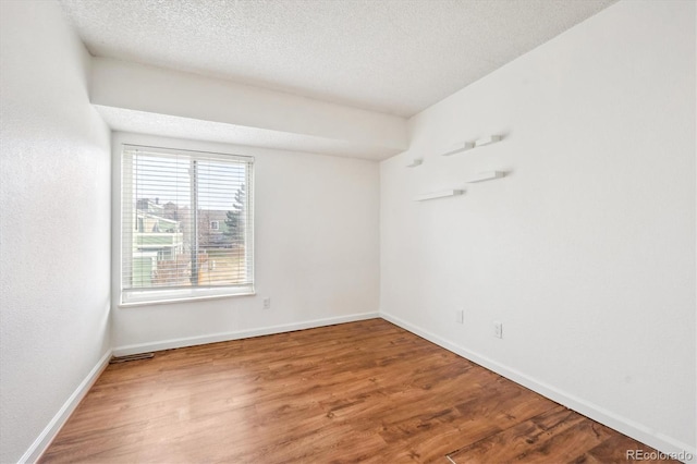 spare room with hardwood / wood-style flooring and a textured ceiling