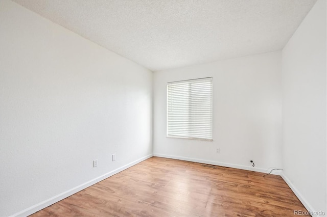 spare room featuring a textured ceiling and light wood-type flooring