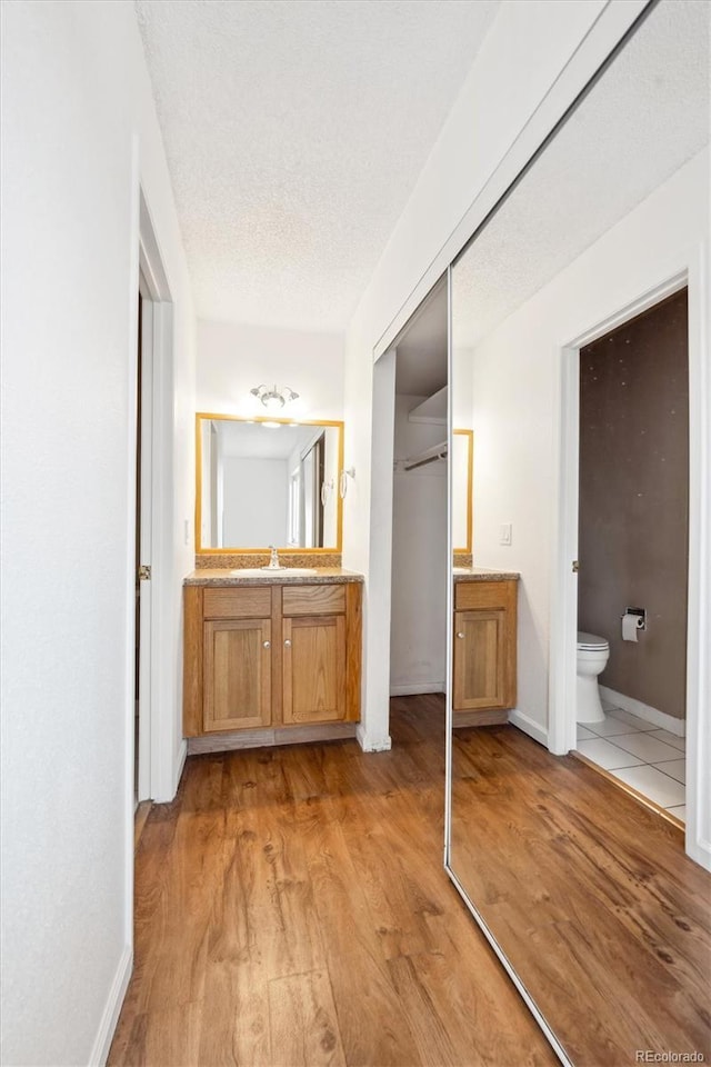 bathroom featuring hardwood / wood-style flooring, vanity, toilet, and a textured ceiling