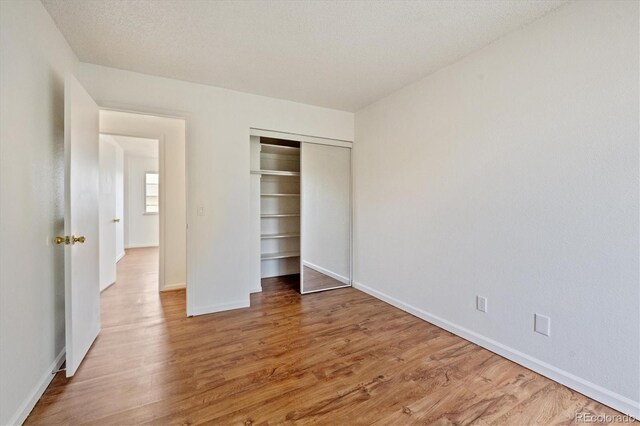 unfurnished bedroom featuring a closet, hardwood / wood-style floors, and a textured ceiling