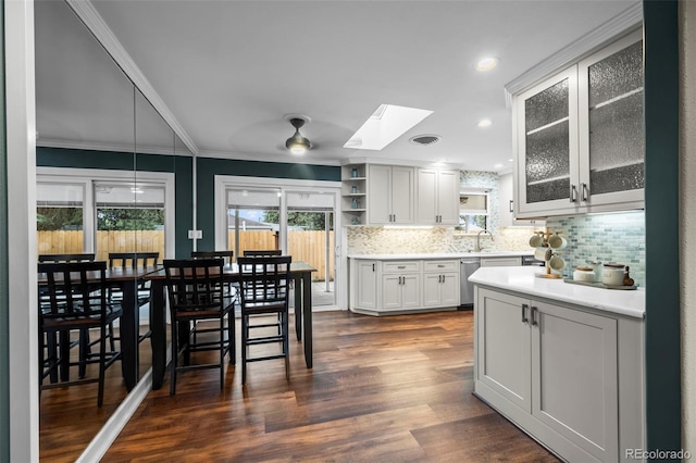 5320 W 62nd Ave, Arvada, CO 80003 - kitchen featuring a skylight, decorative backsplash, crown molding, glass insert cabinets, and dark wood-type flooring