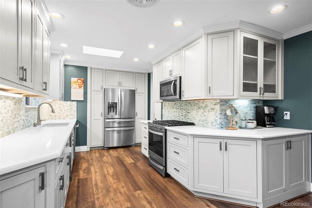5320 W 62nd Ave, Arvada, CO 80003 - kitchen featuring stainless steel appliances, a skylight, glass insert cabinets, tasteful backsplash, and light countertops