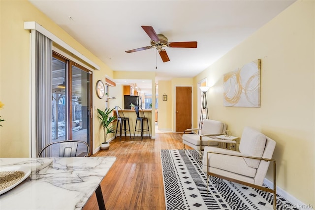 interior space with baseboards, ceiling fan, and light wood finished floors