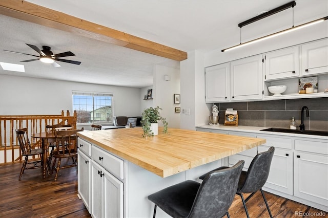 kitchen featuring white cabinetry, wooden counters, a kitchen bar, and a center island