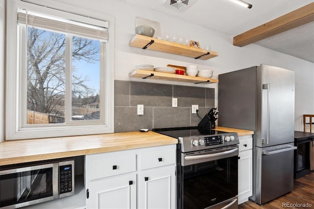 kitchen featuring white cabinetry, stainless steel appliances, wooden counters, and decorative backsplash