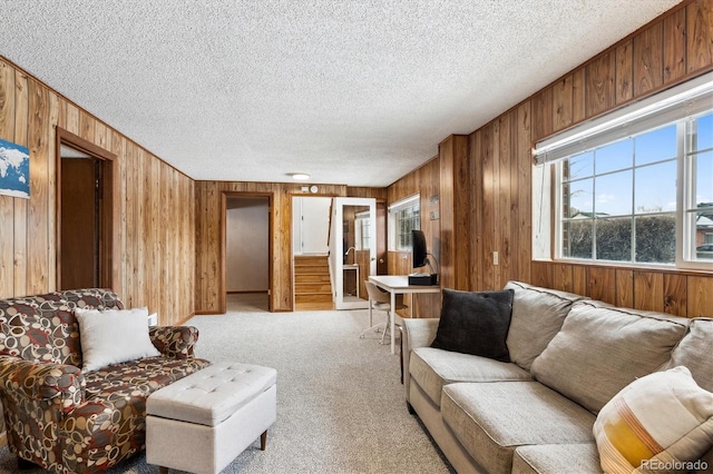 carpeted living room with wooden walls and a textured ceiling