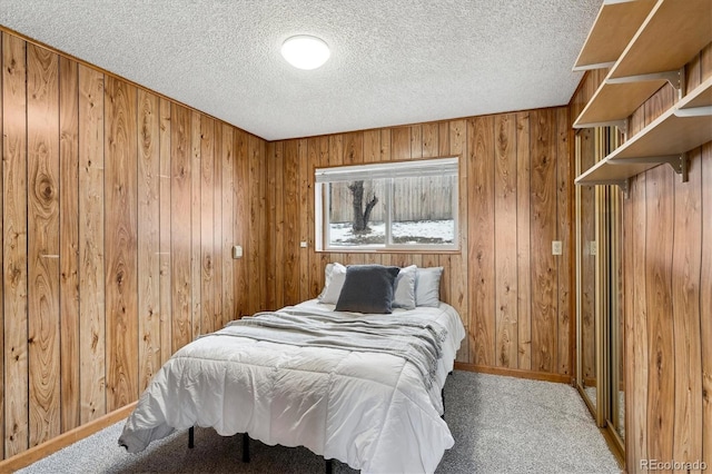 bedroom featuring carpet floors, wooden walls, and a textured ceiling