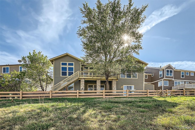 rear view of house featuring a wooden deck and a lawn