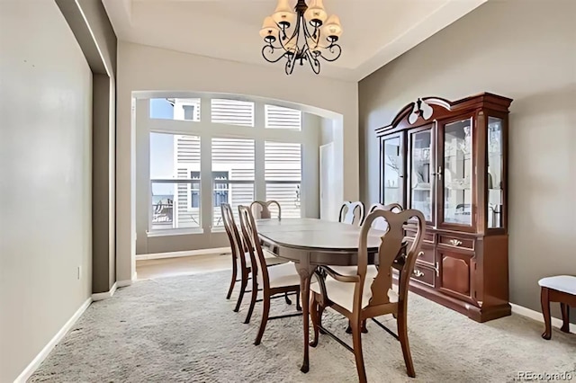 carpeted dining room featuring a notable chandelier