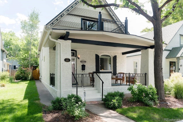 view of front of house with a porch, a front lawn, a balcony, and stucco siding