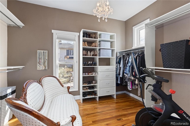 walk in closet with a notable chandelier and wood finished floors