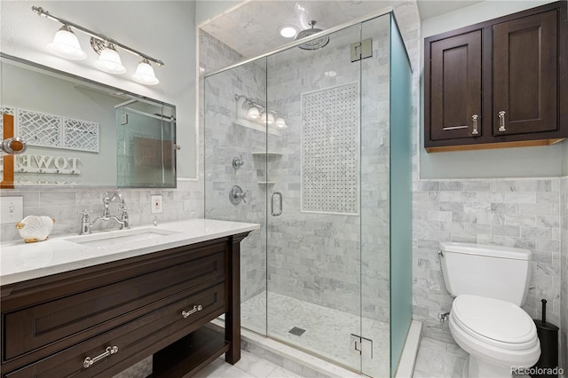 bathroom with tile walls, marble finish floor, a shower stall, and vanity