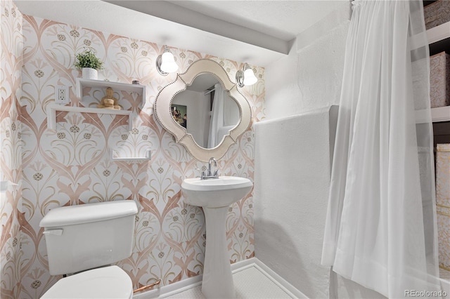 bathroom with baseboards, toilet, and wallpapered walls