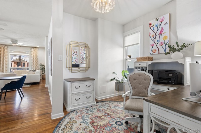 office with ceiling fan with notable chandelier, baseboards, and wood finished floors