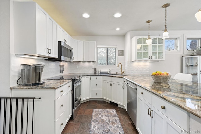 kitchen featuring decorative backsplash, appliances with stainless steel finishes, light stone counters, and a sink