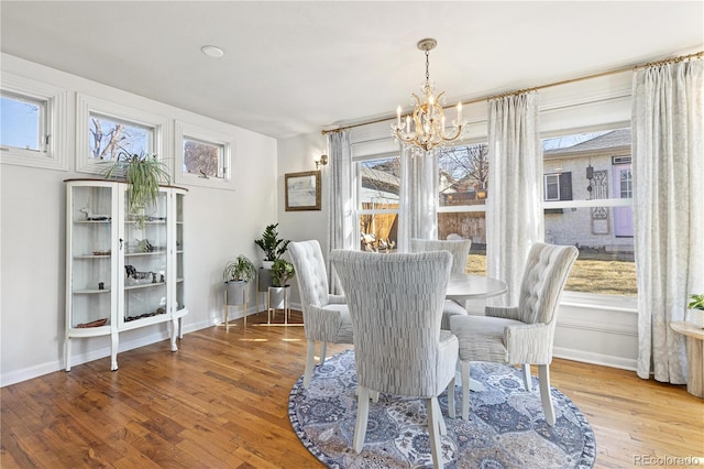 dining room featuring a chandelier, baseboards, and wood finished floors