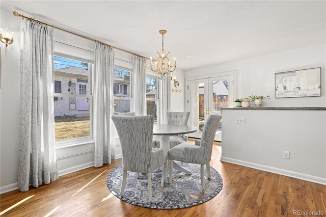 dining room featuring a chandelier, french doors, baseboards, and hardwood / wood-style flooring