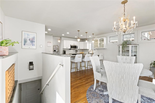 dining room featuring light wood-type flooring, a notable chandelier, and recessed lighting