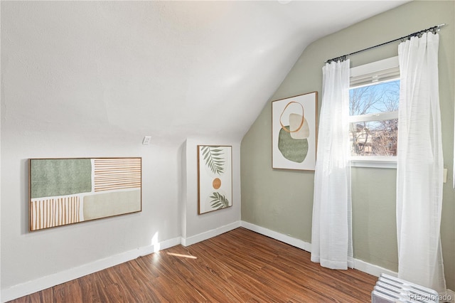 bonus room with baseboards, vaulted ceiling, and wood finished floors