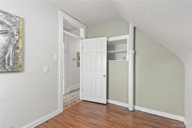 interior space featuring vaulted ceiling, baseboards, arched walkways, and wood finished floors