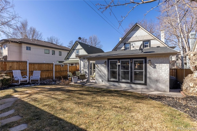 back of property with a patio area, a chimney, fence, and a lawn