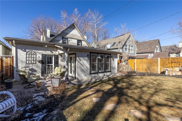 back of property featuring a patio, a chimney, fence, and a lawn