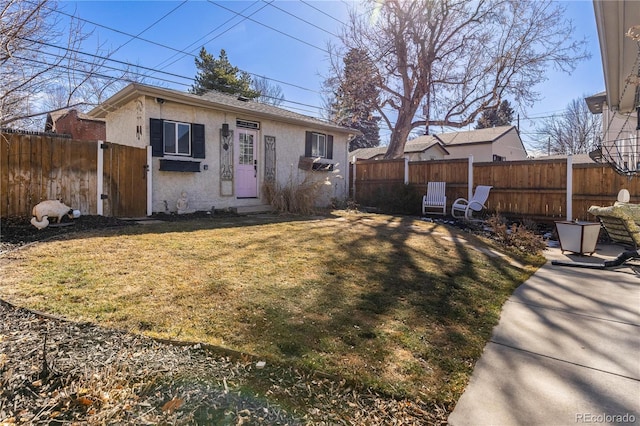 view of front facade with a front yard, fence, and stucco siding