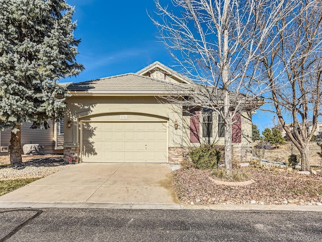 view of front of house featuring a garage, a tile roof, driveway, stone siding, and stucco siding