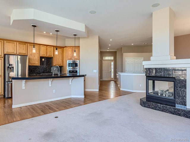 kitchen with pendant lighting, backsplash, hardwood / wood-style flooring, a kitchen bar, and stainless steel appliances