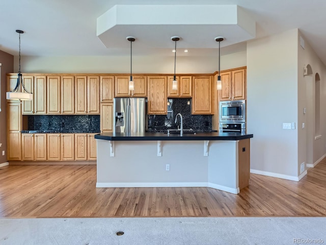 kitchen with decorative backsplash, stainless steel appliances, decorative light fixtures, and light wood-type flooring