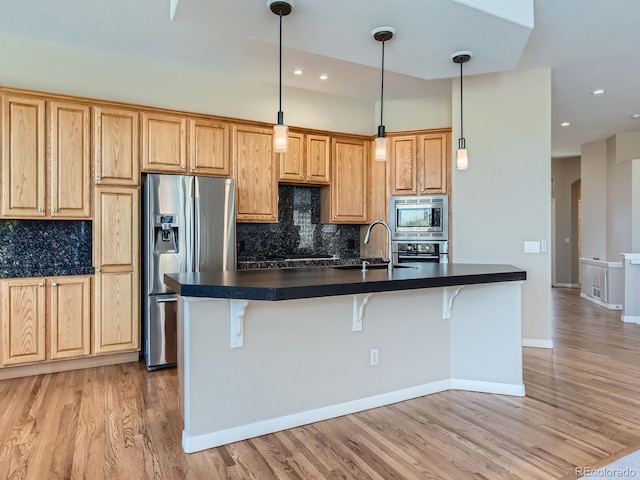 kitchen featuring tasteful backsplash, a breakfast bar area, stainless steel appliances, and light wood-type flooring