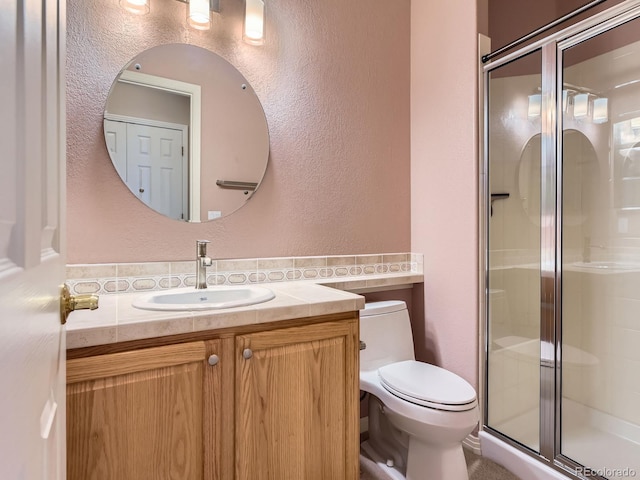 bathroom with vanity, a shower with shower door, and toilet