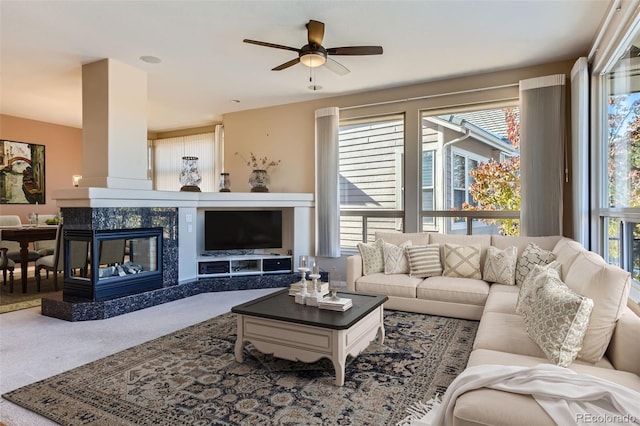 carpeted living room with a premium fireplace, ceiling fan, and a healthy amount of sunlight