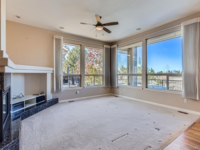 unfurnished living room featuring a high end fireplace, hardwood / wood-style floors, and ceiling fan