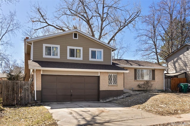 split level home with brick siding, an attached garage, concrete driveway, and fence