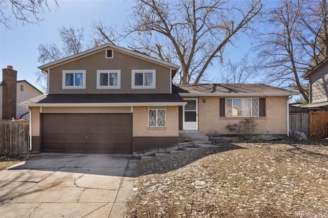 tri-level home with brick siding, a shingled roof, fence, a garage, and driveway