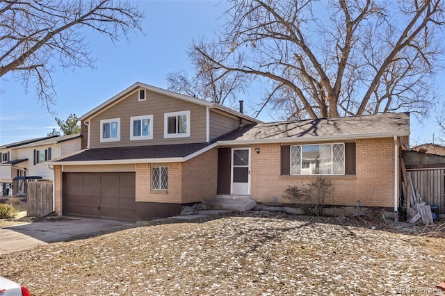 split level home with brick siding, an attached garage, a shingled roof, and driveway