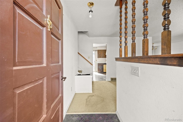 hallway with baseboards, visible vents, stairs, a textured ceiling, and carpet flooring