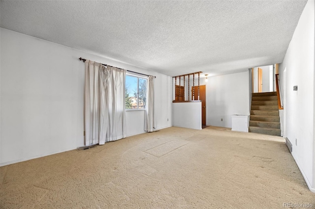 unfurnished living room with stairway, a textured ceiling, and carpet floors