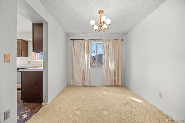 unfurnished dining area with an inviting chandelier, carpet flooring, baseboards, and a textured ceiling