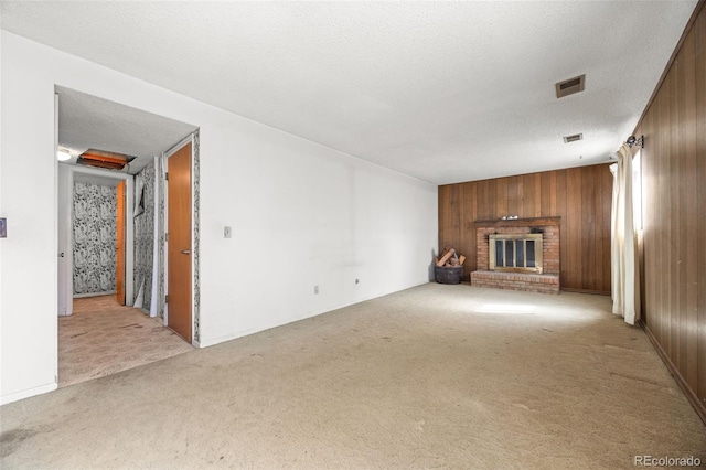 unfurnished living room with visible vents, carpet floors, a textured ceiling, and wood walls