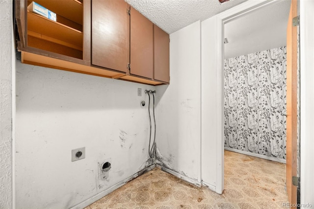 clothes washing area featuring cabinet space, hookup for an electric dryer, and a textured ceiling